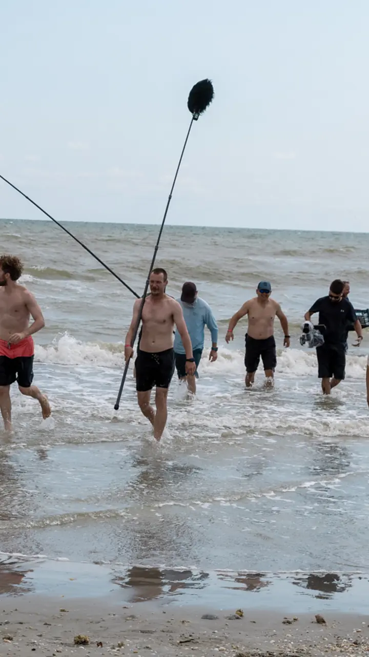 Echipa de filmare intrând în mare cu boom-ul de sunet